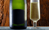 Bottom half of Champagne bottle beside a glass on a wooden background