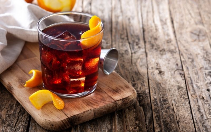 A glass of Cocktail garnished with orange peel