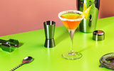 Cocktail with a rim and bar tools on a green table