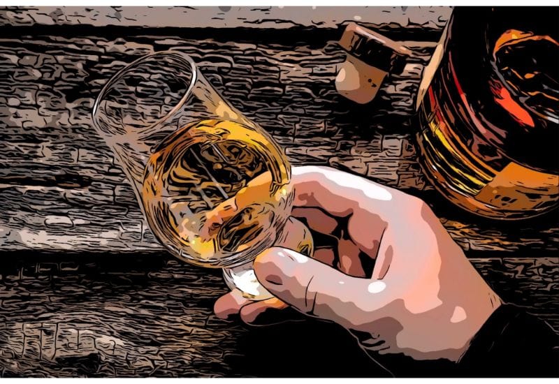 Hand holding a whiskey in a glass for tasting on a wooden background