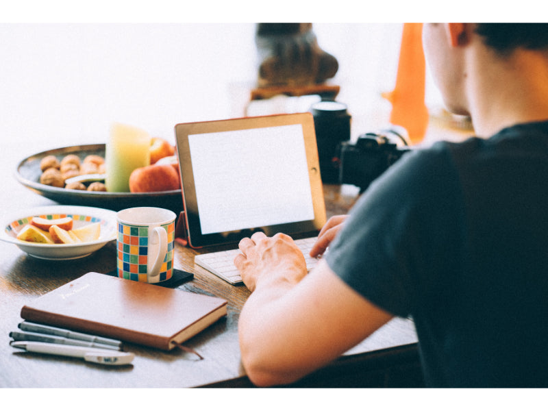 Man writing article on laptop with food and drinks on the table